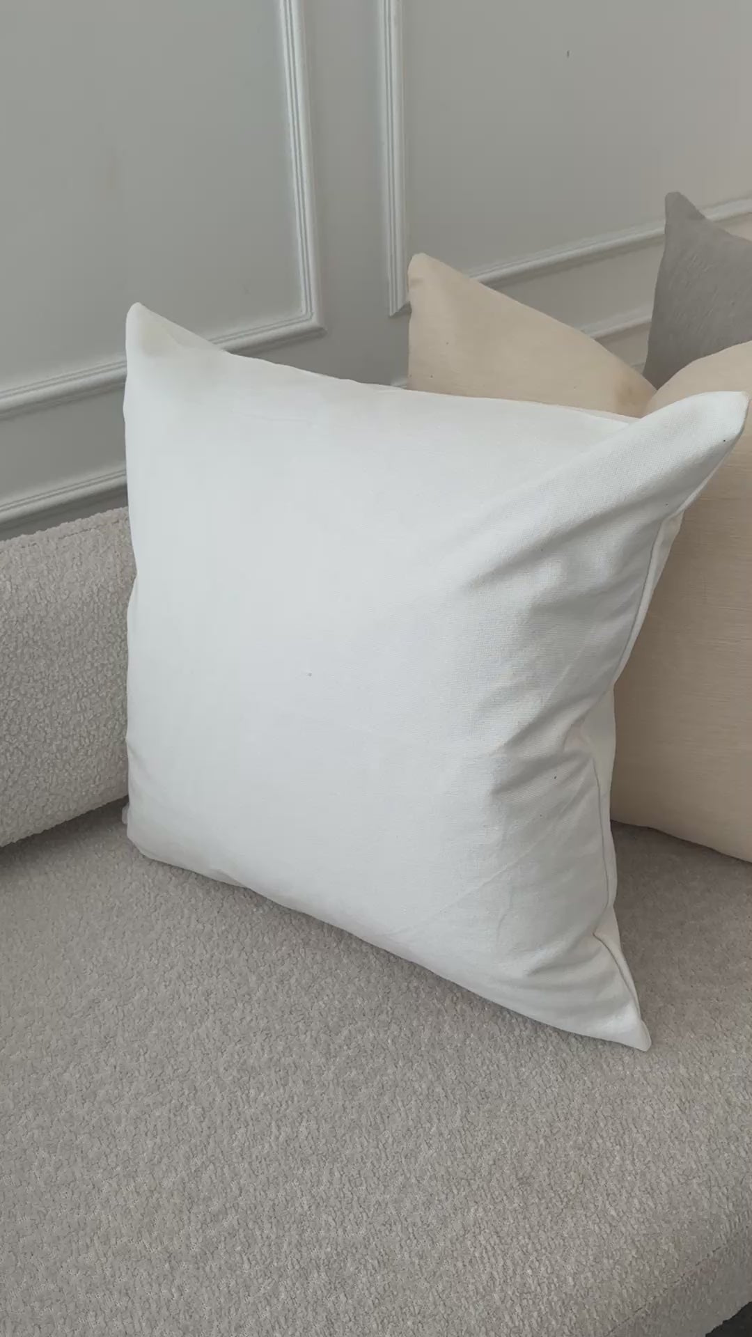A video of the sofa with a crisp white pillow placed in front of beige and navy cushions, underscoring the refined simplicity, durability, and toxin‑free comfort of Tierra’s 100% organic cotton accent pillow cover. Together, the images reflect elevated home comfort, expert craftsmanship, and the effortless beauty of natural materials.