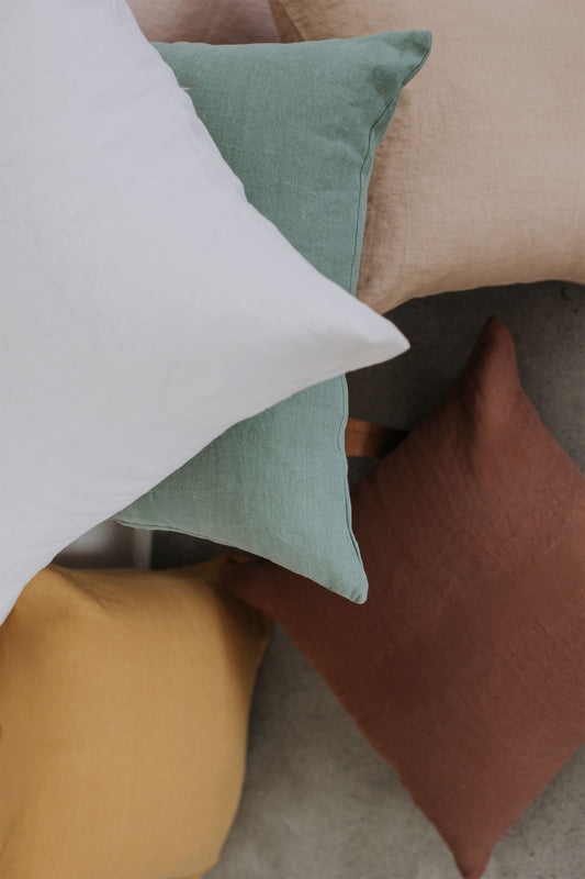 The scene showcases Tierra’s 100% linen Accent Pillow Covers gathered together for visual effect. It features a grouping of every color offered, highlighting the plush, breathable texture of 100% linen. 