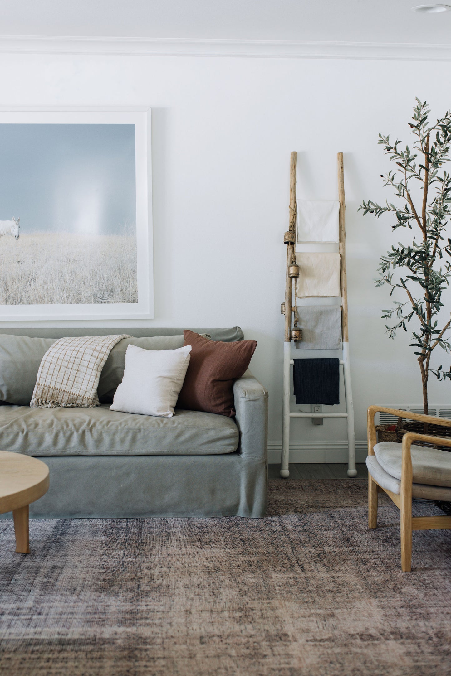 Beach-inspired living room with gray sofa, wooden coffee table, and Tierra's 100% linen accent pillows in white and brown colors creating a relaxed lived-in coastal aesthetic.