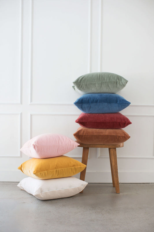 The scene showcases Tierra’s Organic Velvet Accent Pillow Cover styled in a variety of cozy, elevated home settings. It features a grouping of soft beige and blush pillows arranged near a sunlit window, highlighting the plush, breathable texture of organic velvet.