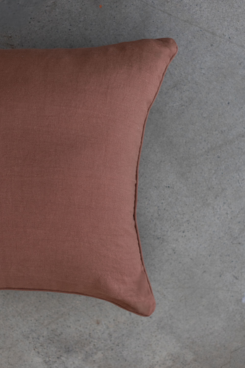 The scene highlights Tierra’s 100% Linen Headboard Cushion Cover through a series of soft, neutral bedroom scenes. It shows a smooth brown pillow resting against a muted backdrop, emphasizing the clean, breathable feel of natural linen. 