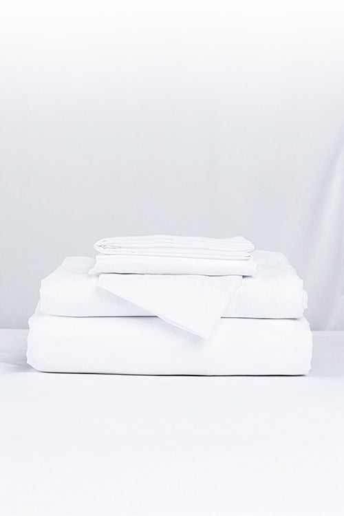 A stack of folded white linens, underscoring the sheet’s easy‑care nature and durability.